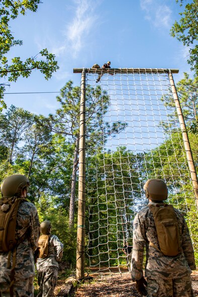 Airmen from the 919th Special Operations Security Forces Squadron watch as a training cadre member demonstrates proper techniques for the cargo net obstacle May 5, 2018 on Eglin Air Force Base, Fla.