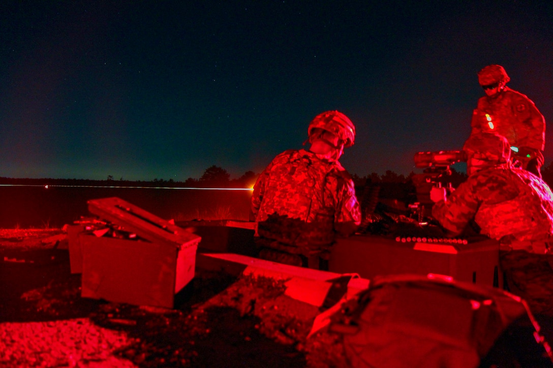 Soldiers fire weapons at night.