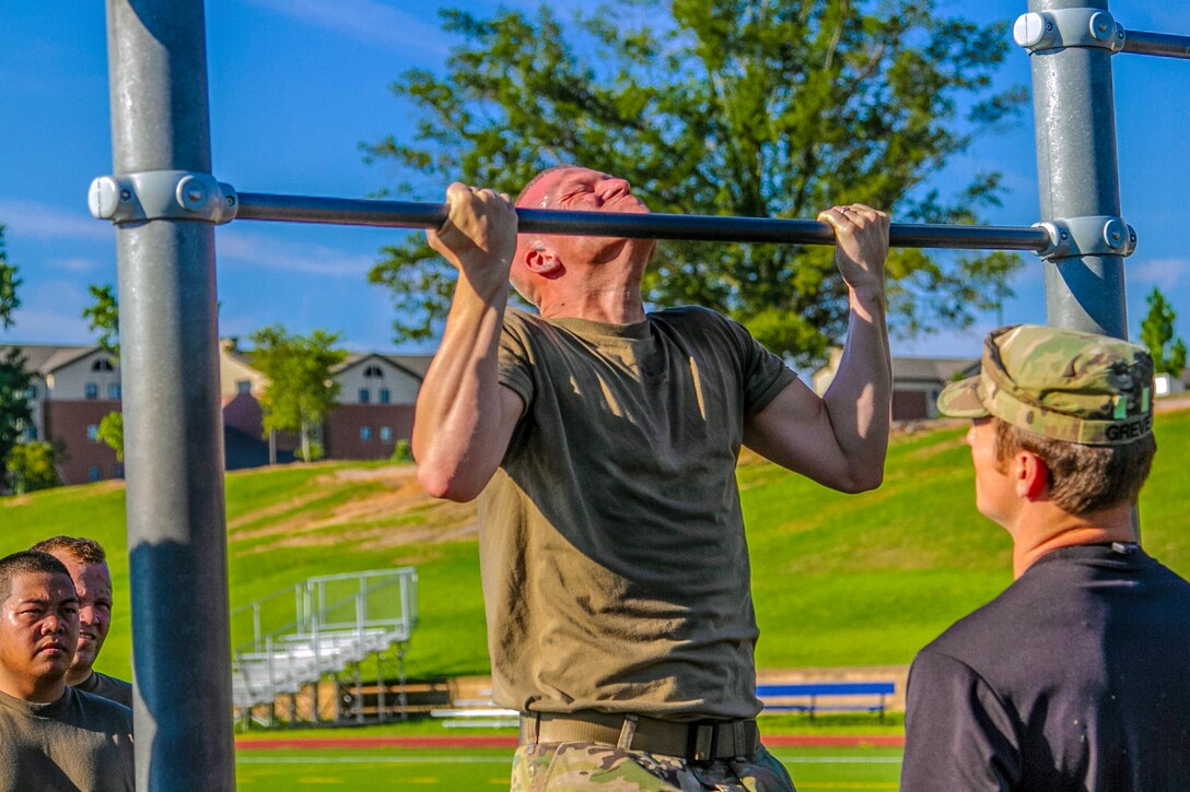 A soldier does a pullup on a bar.