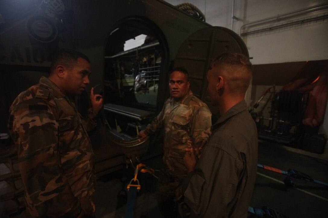 A U.S. Marine crewman with Combat Assault Company, 3rd Marine Regiment, shows Tongan Marines the safety measures of boarding an AAV-P7/A1 assault amphibious vehicle aboard the Royal Australian Navy landing helicopter dock ship HMAS Adelaide (L01) during Rim of the Pacific (RIMPAC) exercise off the coast of Marine Corps Base Hawaii July 11, 2018. RIMPAC provides high-value training for task-organized, highly capable Marine Air-Ground Task Force and enhances the critical crisis response capability of U.S. Marines in the Pacific. Twenty-five nations, 46 ships, five submarines, about 200 aircraft and 25,000 personnel are participating in RIMPAC from June 27 to Aug. 2 in and around the Hawaiian Islands and Southern California. The world's largest international maritime exercise, RIMPAC provides a unique training opportunity while fostering and sustaining cooperative relationships among participants critical to ensuring the safety of sea lanes and security on the world's oceans.