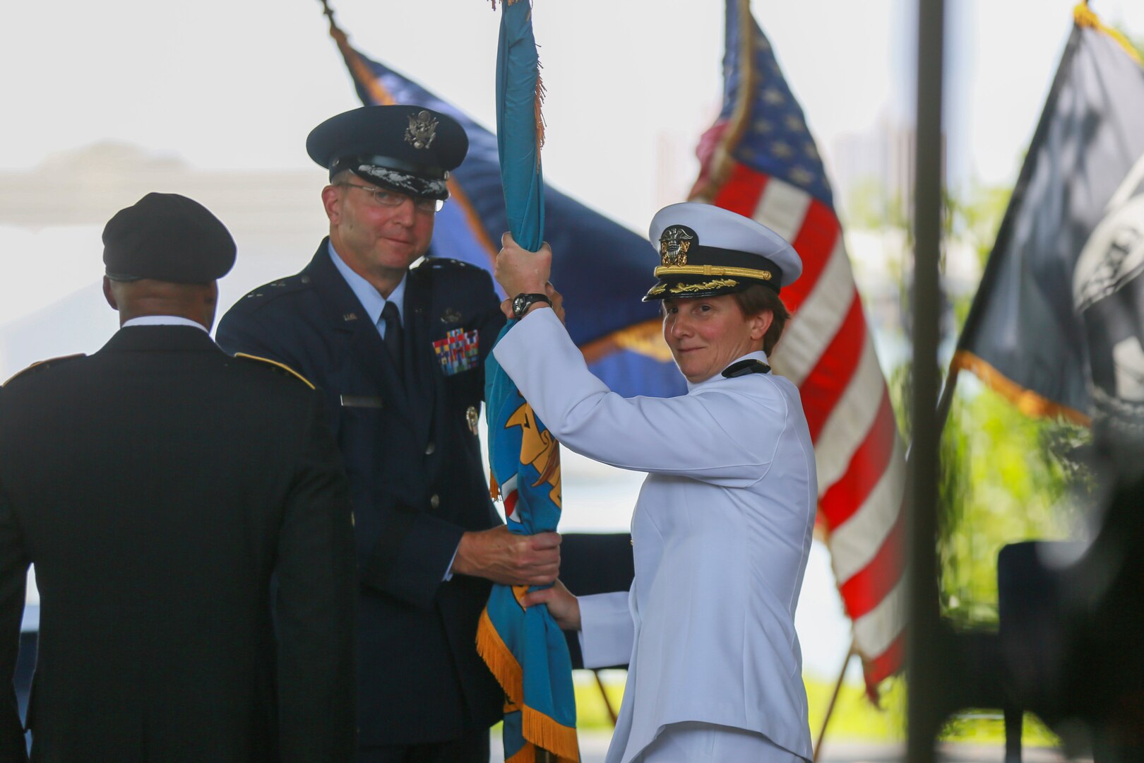 DLA Logistics Operations Director Air Force Maj. Gen. Mark Johnson passes the DLA flag to incoming DLA Pacific Commander Navy Capt. Kristin Acquavella, during a change of command at Nob Hill on historic Ford Island, Pearl Harbor, Hawaii July 10.(Photo by Marine Cpl. Patrick Mahoney)