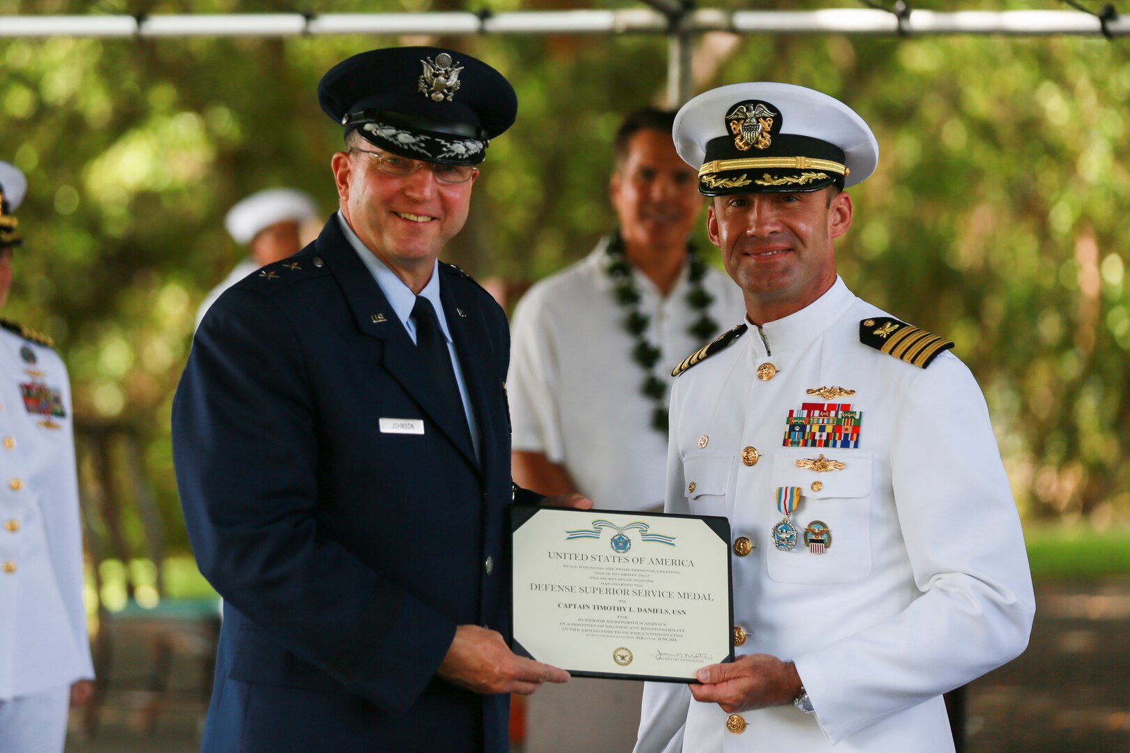 Navy Capt. Timothy Daniels (right) is presented his Defense Superior Service award by Air Force Maj. Gen. Mark Johnson as the outgoing DLA Pacific commander, in a July 10 ceremony at Nob Hill on historic Ford Island, Pearl Harbor, Hawaii (Photo by Marine Cpl. Patrick Mahoney)