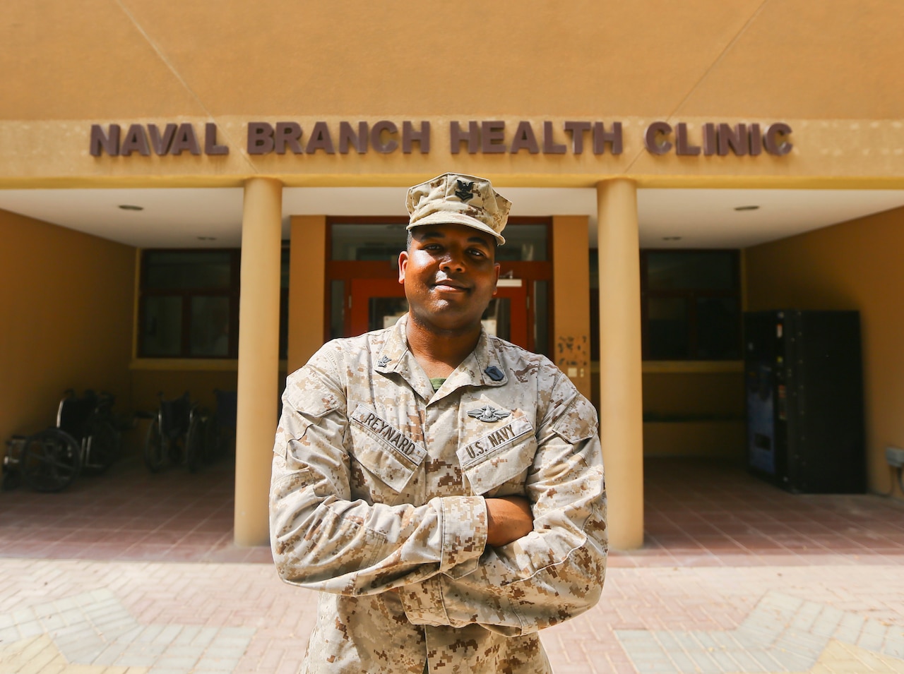 A sailor poses for a photo in front of a medical clinic.