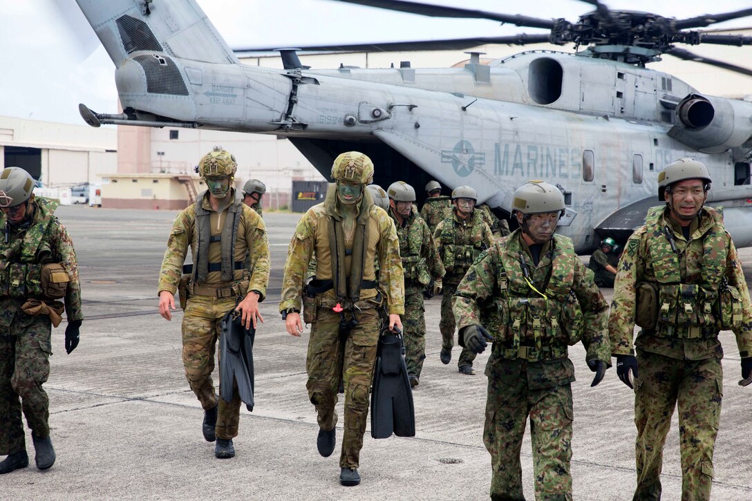 Australian and Japanese soldiers disembark a helicopter.