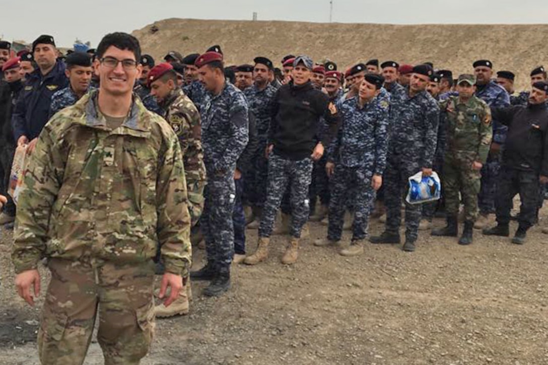 An Army sergeant stands in front of a group of service members in Iraq.