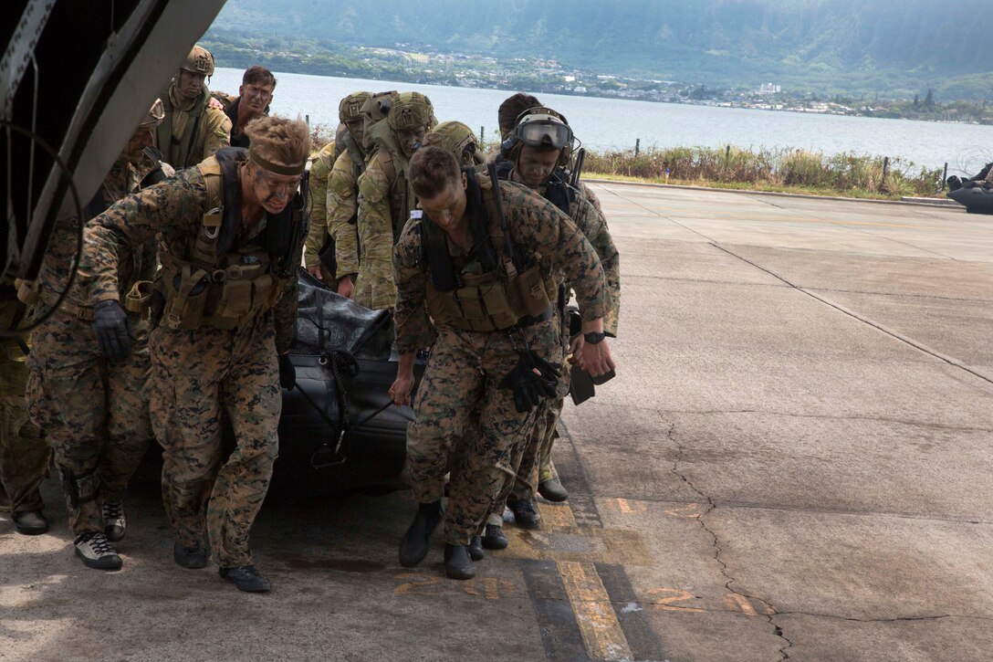 U.S. Marines and Australian soldiers load a combat rubber raiding craft onto a helicopter.