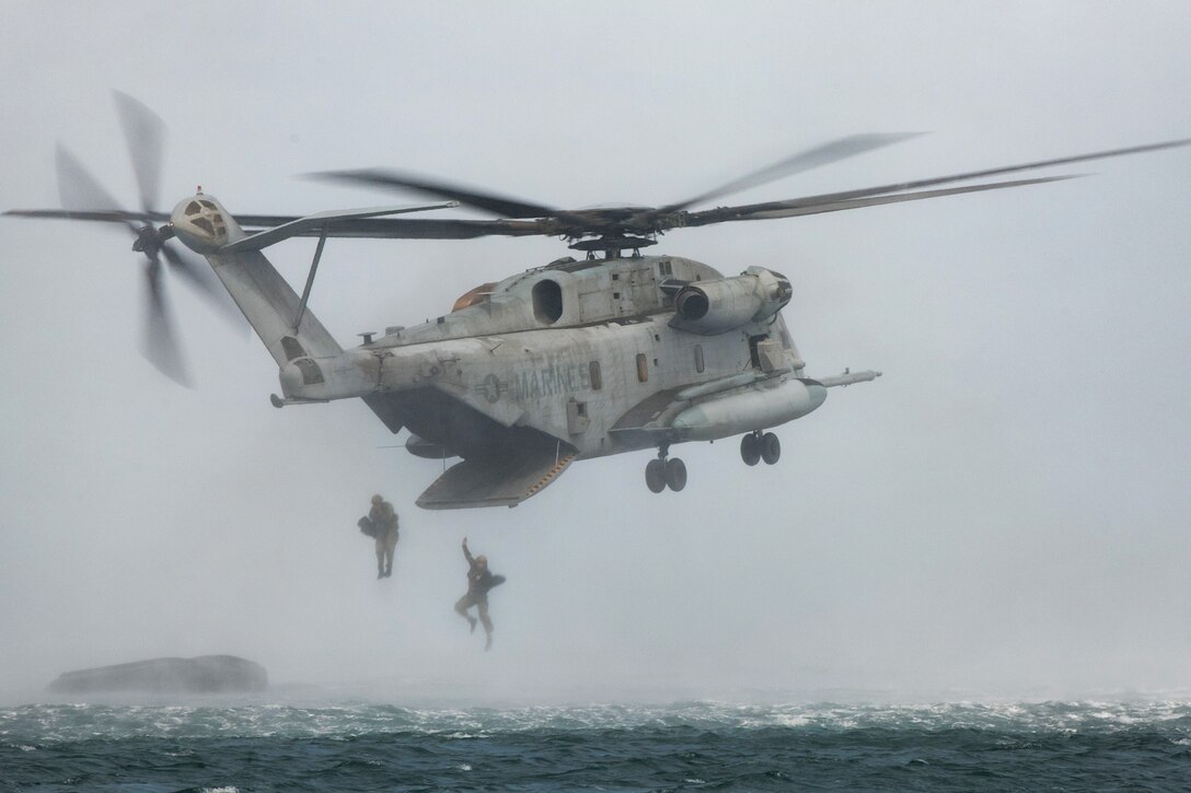 U.S. Marines and Canadian troops jump from a CH-53E Super Stallion helicopter.