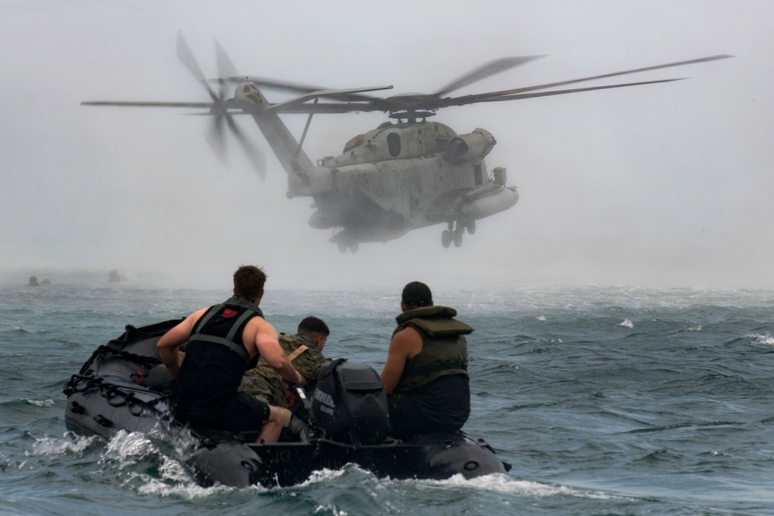 U.S. Marines watch a CH-53E Super Stallion helicopter depart the drop zone.