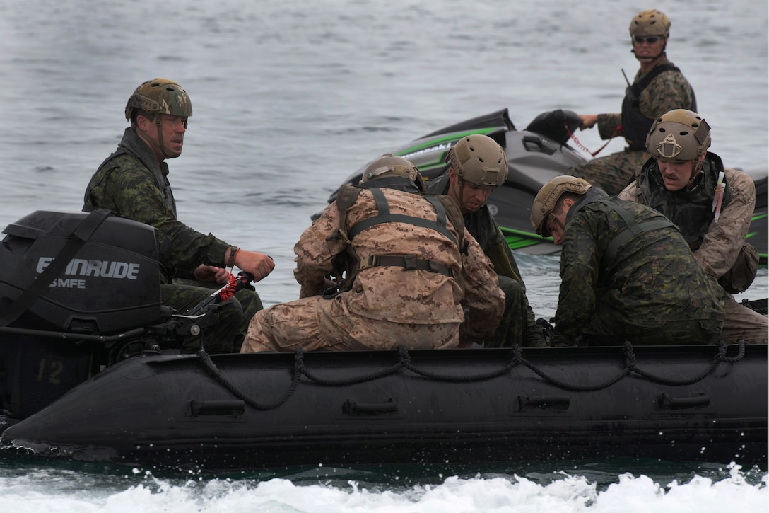 U.S. Marines and Canadian troops prepare to depart the drop zone.