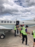 “U.S. Embassy, Bangkok Air Attaché, Maj. Christopher Coffman, USAF, unloads Meals Ready to Eat (MREs) from his Bangkok-based Defense Attaché Service C-12 aircraft, and hands them to Chiang Rai airport personnel for transfer to the cave complex rescue site. The MREs provided vital nutrition for the trapped youth soccer team shortly after they were found alive."
