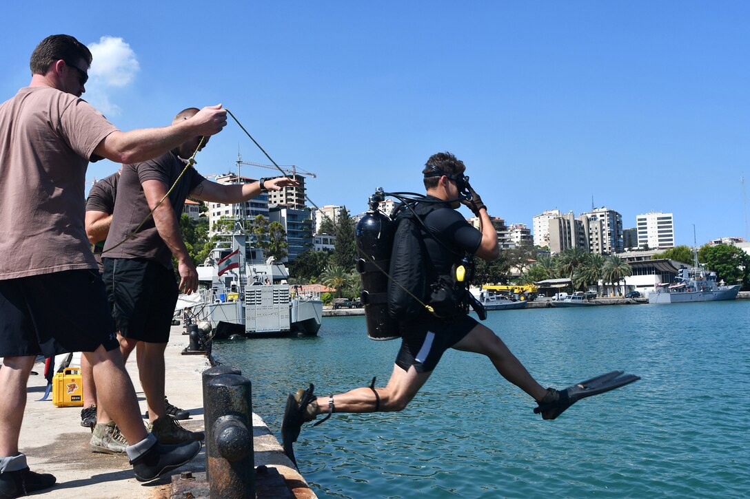 A sailor performs a front water entry dive.