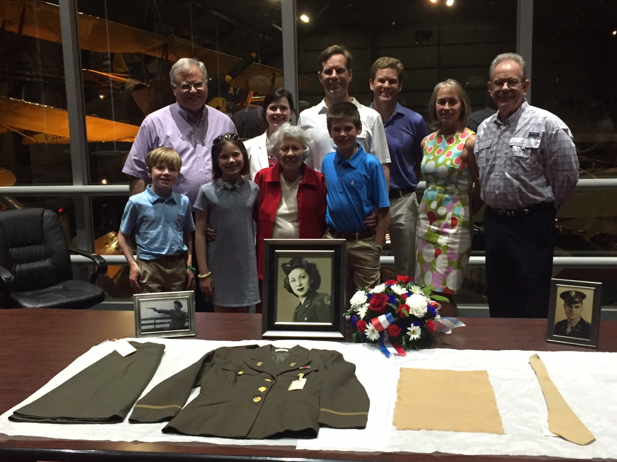 Yolanda ‘Tipi’ Minnehan stands with two of her three children, some of their children and some of her great-grandchildren July 6 at the National Museum of the U.S. Air Force as they admire her uniform artifacts from the Women’s Army Auxiliary Corps, later the Women’s Army Corps. U.S. Air Force Col. Barney Minnehan, whose final active-duty assignment was at Wright-Patterson AFB, is pictured far right. (Skywrighter photo/Amy Rollins)