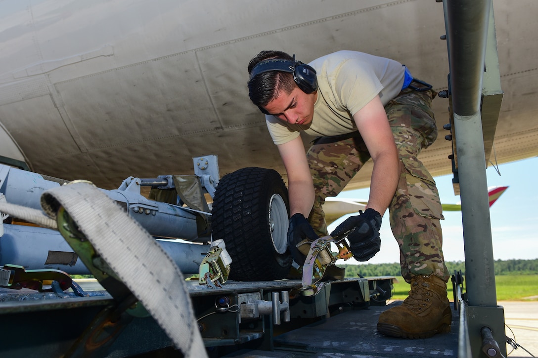 An Air Force airman tightens up and secures cargo straps around a loading platform.