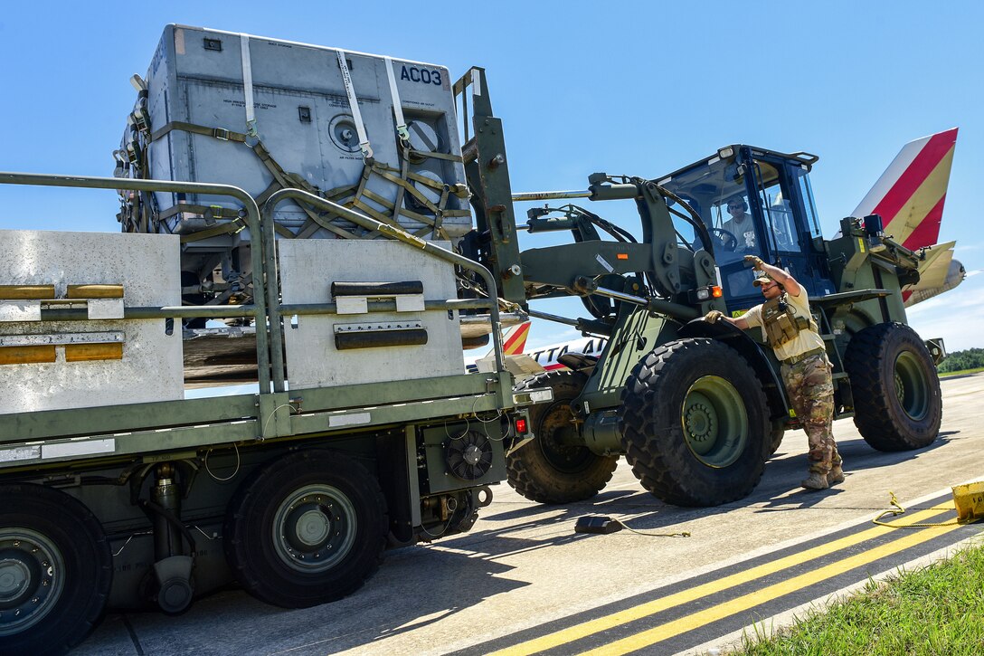 An Air Force loadmaster guides an airman operating a forklift.