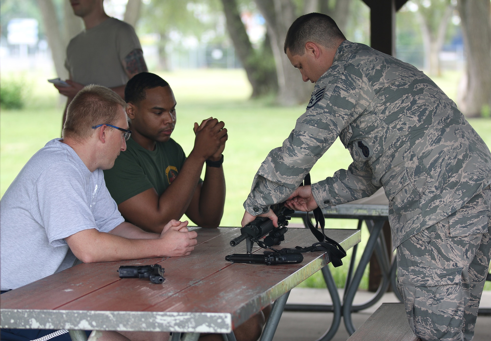 Senior Airman Markell Lawson and Staff Sgt. Steven Branham, 445th Aerospace Medicine Squadron, receive weapons handling training from Staff Sgt. Jordan Helphrey, 445th Security Forces Squadron, as a part of a team building exercise here June 6, 2018.