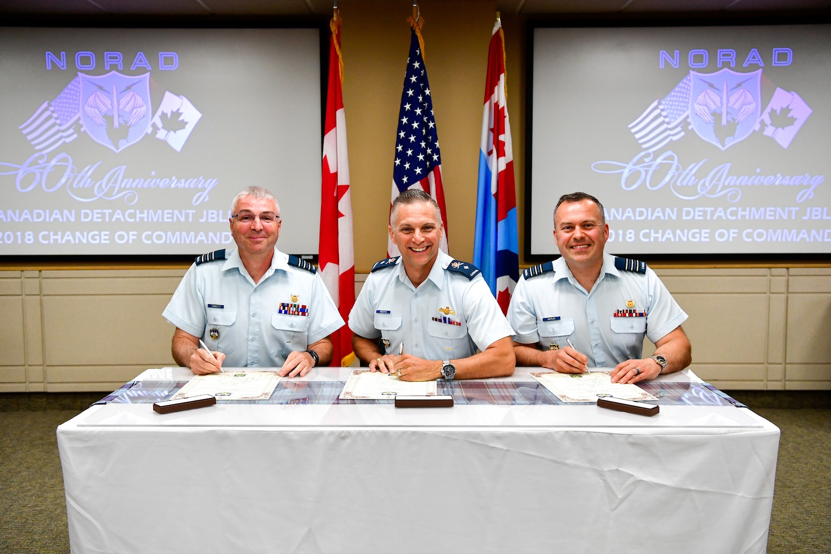 Canadian Brig. Gen. Sylvain Menard (center), Continental U.S. North American Aerospace Defense Region (CONR) deputy commander, presides over the Western Air Defense Sector Canadian Detachment change of command. Lt. Col. Michael Fawcett (left) assumes command from the outgoing commander, Lt. Col. Matthew Wappler (right), during the ceremonial signing of the change of command scrolls July 10, 2018. (U.S. Air National Guard photo by Kimberly D. Burke)