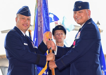 Col. Jimmy Canlas, outgoing 437th Airlift Wing commander, passes the 437th AW guidon to Lt. Gen. Gi Tuck, 18th Air Force commander, during a change of command ceremony July 12, 2018, in Nose Dock 2.