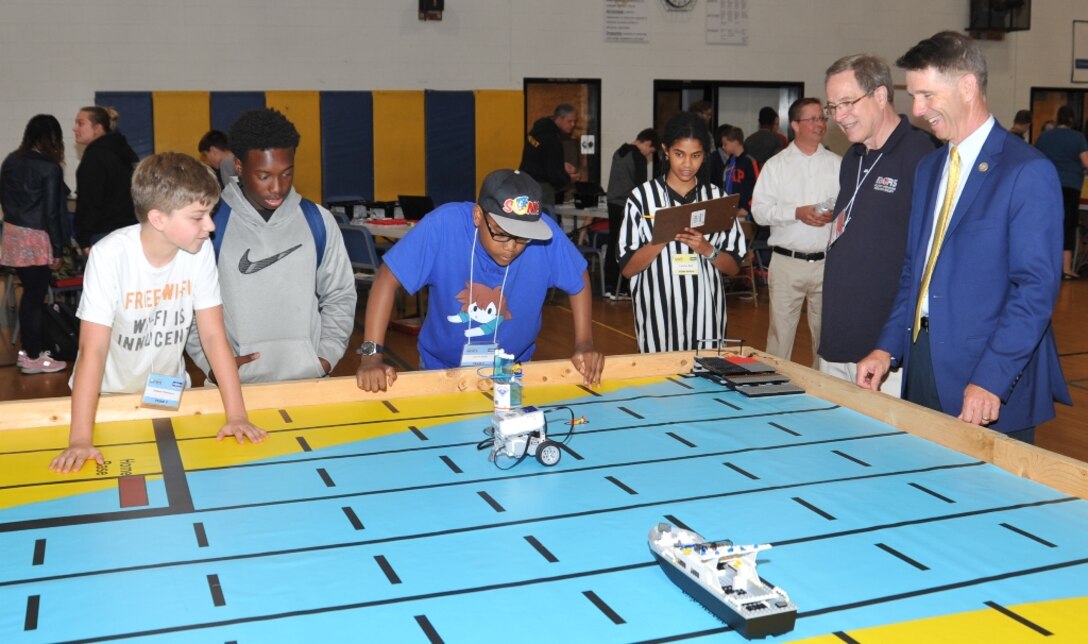 IMAGE: KING GEORGE. Va. (June 25, 2018) - Rep. Rob Wittman (R-Va.) observes middle school students deploy a robot they designed, built, and programmed to deliver humanitarian aid, rotate troops and transport an electromagnetic railgun to the deck of a Navy ship at the 2018 STEM Summer Academy. Students briefed their mentors, teachers, and visitors, including Wittman, on how they overcame a variety of Navy focused problems by designing, building, and programming LEGO Mindstorm robots to solve a variety of Navy focused problems.