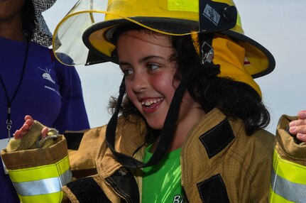 Elizabeth Wyatt, age 8, attempts to put on a firefighter uniform as quickly as possible during a Science, Technology, Engineering, Art and Mathematics (STEAM) event July 12, 2018, at the emergency management building on Joint Base Charleston, S.C.