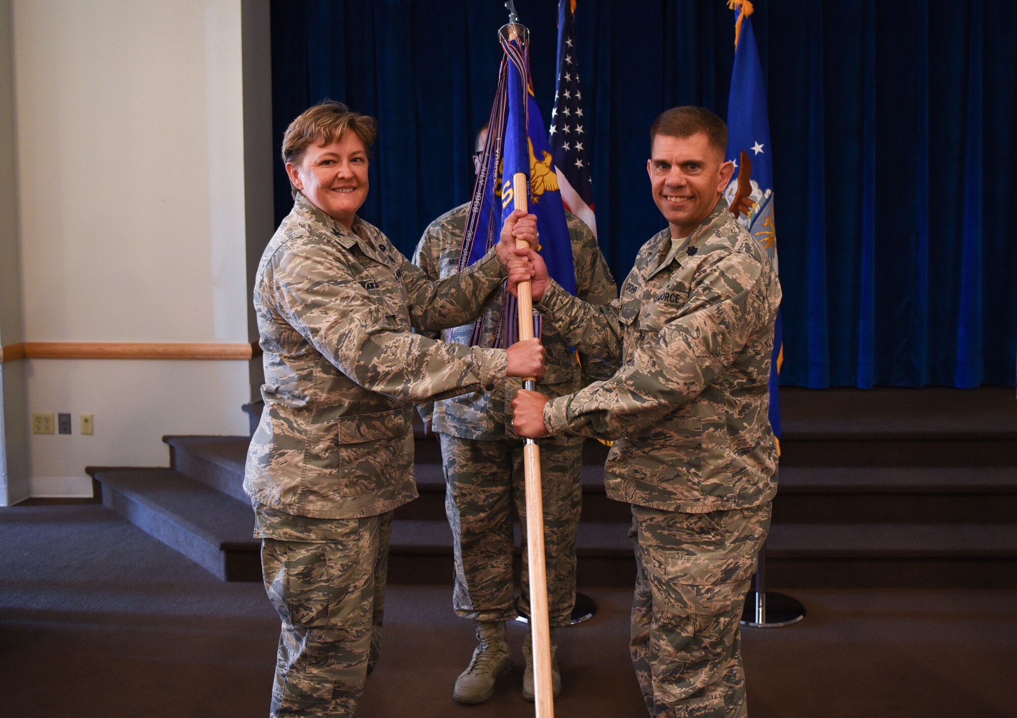 Colonel Tricia Van Den Top, 90th Mission Support Group commander, passes the guidon to Lt. Col. Raymond Spohr, 90th Communications Squadron commander, during the 90th CS change of command ceremony July 13, 2018 at Trails End on F.E. Warren Air Force Base, Wyo. The ceremony signified the transition of command from Lt. Col. Josef Chesney. (U.S. Air Force photo by Airman 1st Class Abbigayle Wagner)