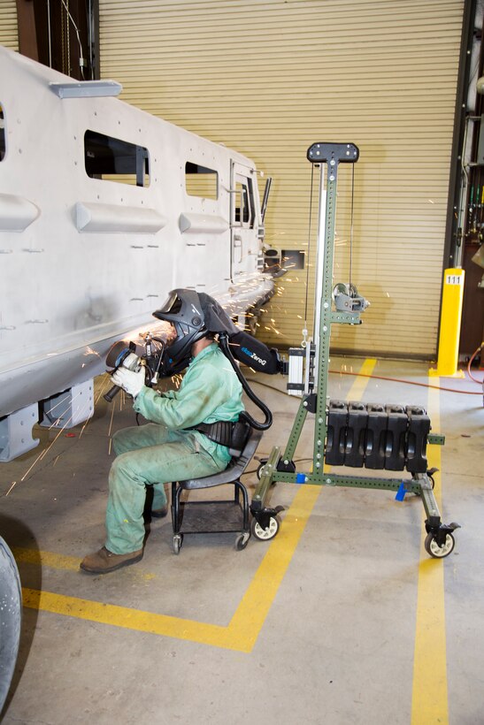 Niels Woods, welder, uses a grinder attached to an Ekso Zero Gravity Arm, to smooth out welds on a Light Armored Vehicle at PPB, MDMC, aboard the Yermo Annex of MCLB Barstow, June 29. The “zero-g” arm counterbalances the 25- to 30-pound weight of the grinder making it easier to use for longer periods without causing stress or muscle injuries to the welder. The arm is also being evaluated for use with other tools.