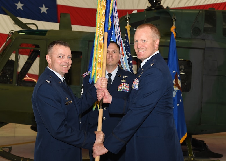 Colonel Joshua Bowman, 582nd Helicopter Group commander, passes the guidon to Lt. Col. Adam Rudolphi, 37th Helicopter Squadron commander, during the 37th HS change of command ceremony July 13, 2018 in Building 1250 on F.E. Warren Air Force Base, Wyo. The ceremony signified the transition of command from Lt. Col. James Cline to Rudolphi. (U.S. Air Force photo by Glenn S. Robertson)