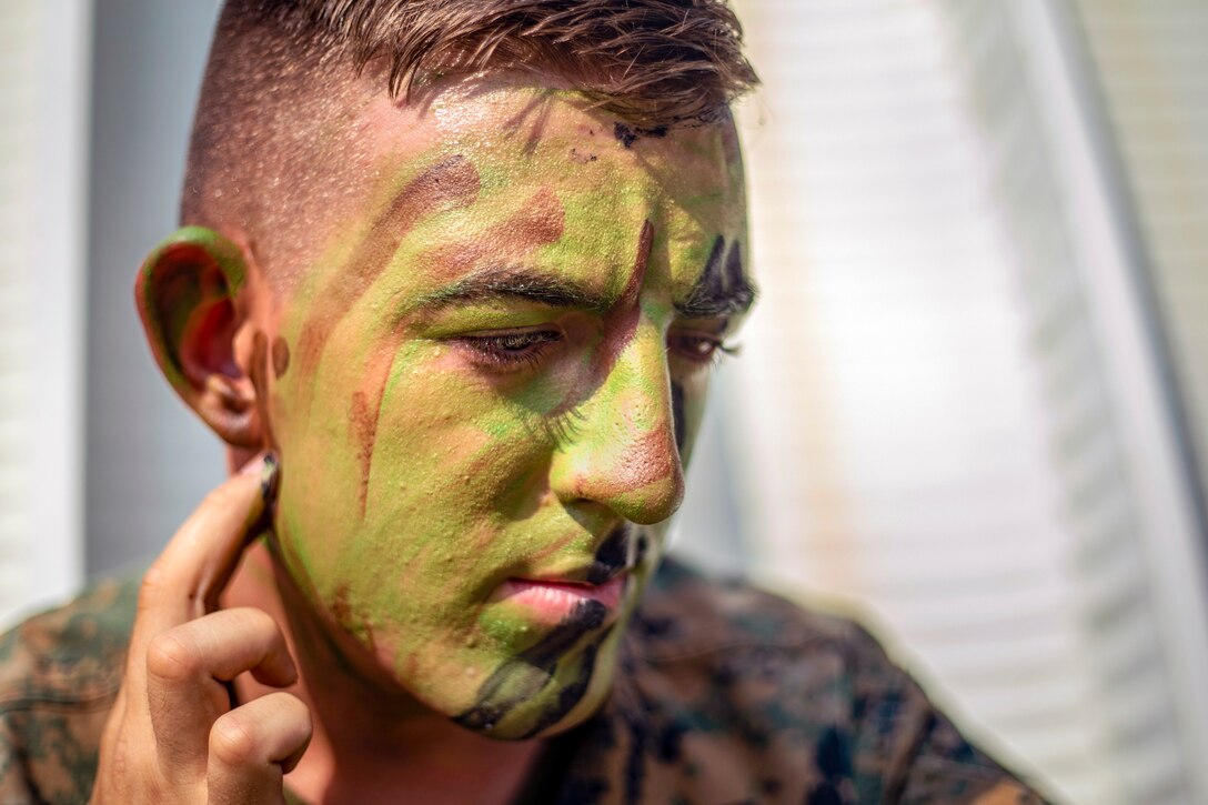 A Marine puts paint on his face.