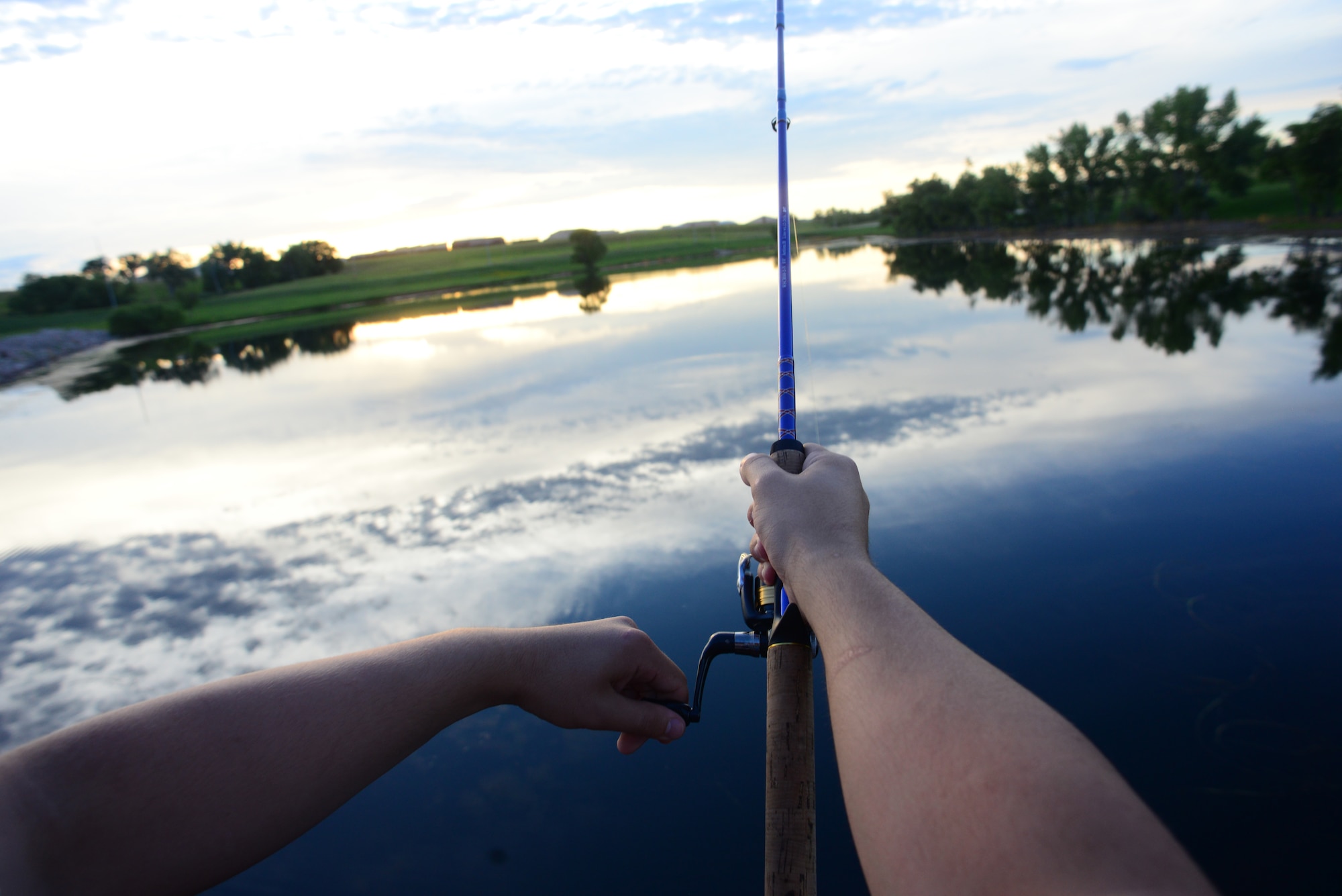 Airman John Ennis, a 28th Bomb Wing Public Affairs broadcast journalist, reels his rod at Gateway Lake on Ellsworth Air Force Base, S.D., July 12, 2018. Some fish species are allowed to be entered in South Dakota fishing records. (U.S. Air Force photo by Airman 1st Class Nicolas Z. Erwin)