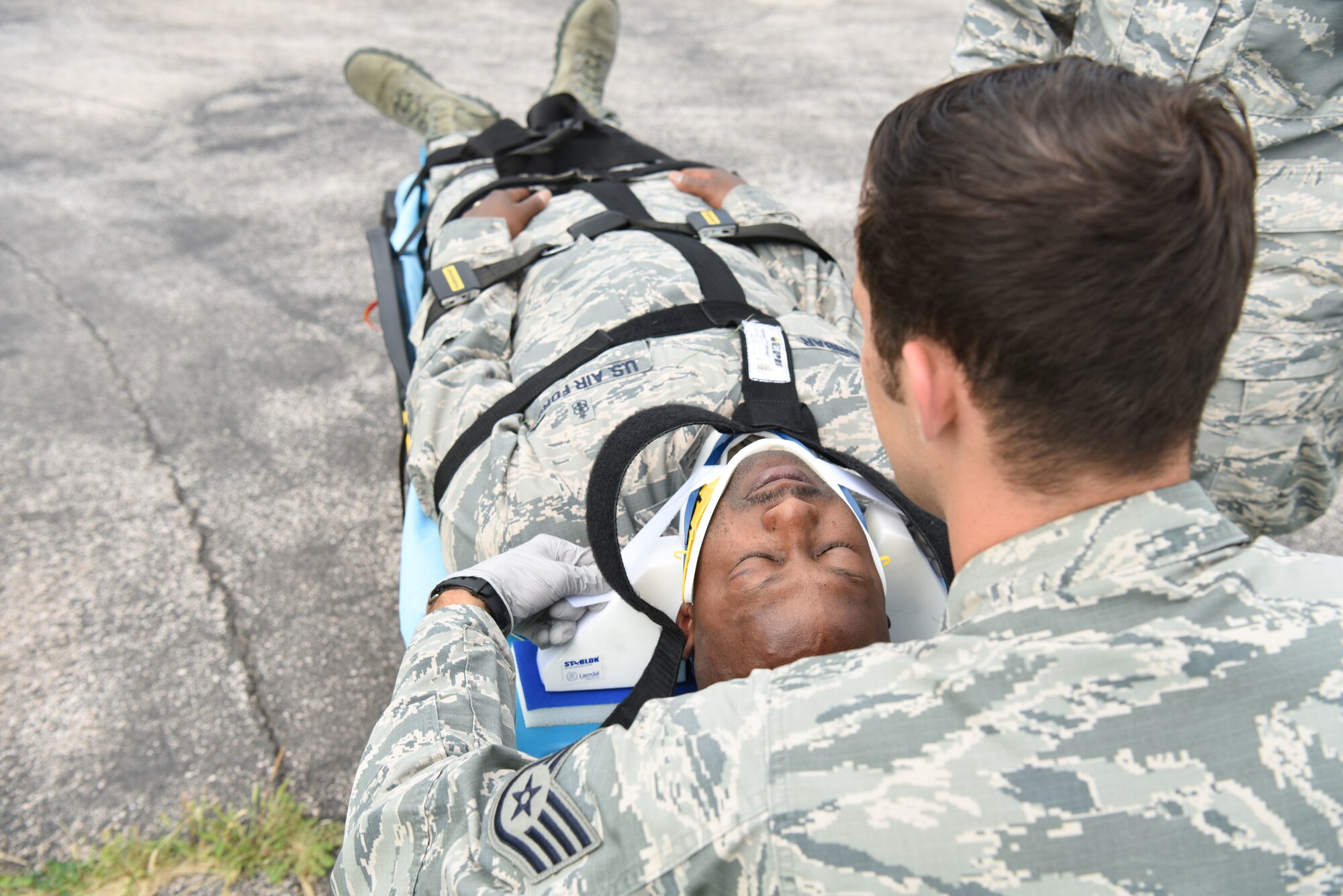 Staff Sgt. Michael Glowth, a 28th Medical Group aerospace medical technician, practices placing head blockers on Tech. Sgt. Ricky Dunbar, the noncommissioned officer in charge of the ambulance services flight at Ellsworth Air Force Base, S.D., July 10, 2018. Aerospace medical technicians go through a 98-day course that prepares them for the stresses and responsibilities of serving in ambulance services. (U.S. Air Force photo by Airman 1st Class Thomas Karol)