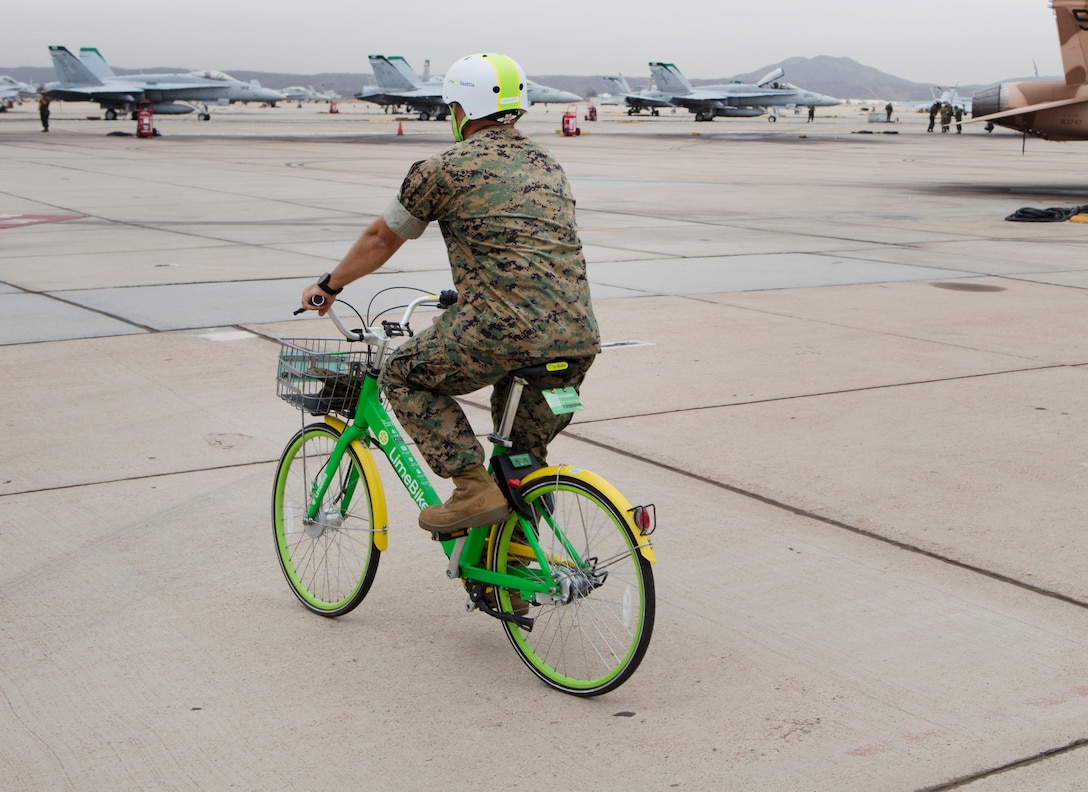 U.S. Marine Corps Maj. Brandon Newell, rides a lime bike on the flightline of Marine Corps Air Station Miramar, Calif., July 9.  MCAS Miramar and LimeBike, a bicycle-sharing company, worked together to bring an environmentally friendly and inexpensive transportation alternative for Marines who lack vehicle transportation or wish to save money.  (U.S. Marine Corps photo by Cpl. Victor Mincy)