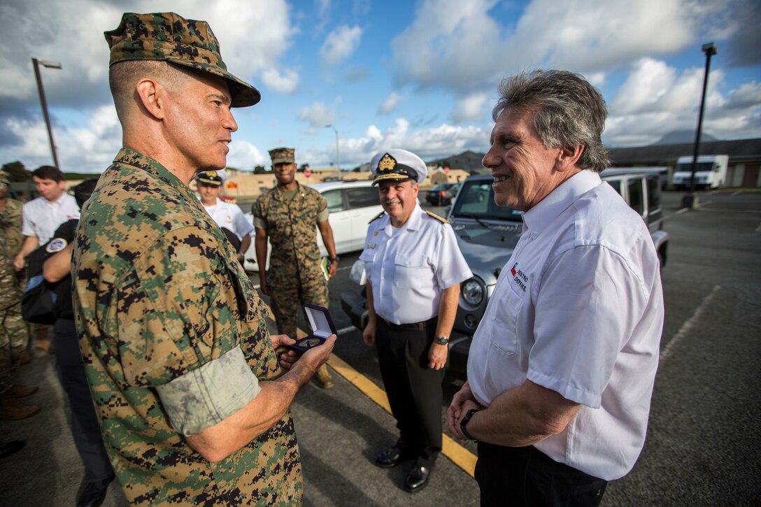 Alberto Espina, right, Chilean Minister of Defense, presents a challenge coin to U.S. Marine Corps Brig. Gen. Mark Hashimoto, component commander, Fleet Marine Force, during Rim of the Pacific (RIMPAC) exercise on Marine Corps Base Hawaii July 11, 2018. RIMPAC provides high-value training for task-organized, highly capable Marine Air-Ground Task Force and enhances the critical crisis response capability of U.S. Marines in the Pacific.