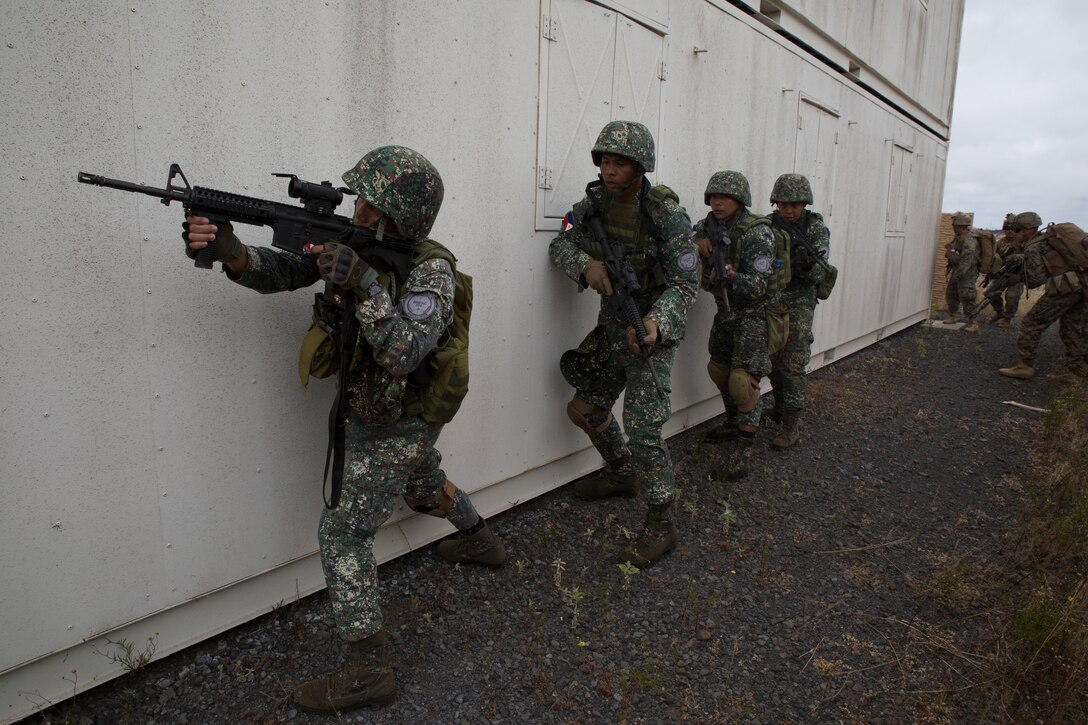 Philippine and U.S. Marines stack alongside a building to engage enemy combatant role players during a noncombatant evacuation operation (NEO) training event as part of Rim of the Pacific (RIMPAC) exercise at Pohakuloa Training Area, Hawaii, July 12, 2018. A NEO is conducted to evacuate citizens whose lives are in danger. RIMPAC provides high-value training for task-organized, highly capable Marine Air-Ground Task Force and enhances the critical crisis response capability of U.S. Marines in the Pacific.