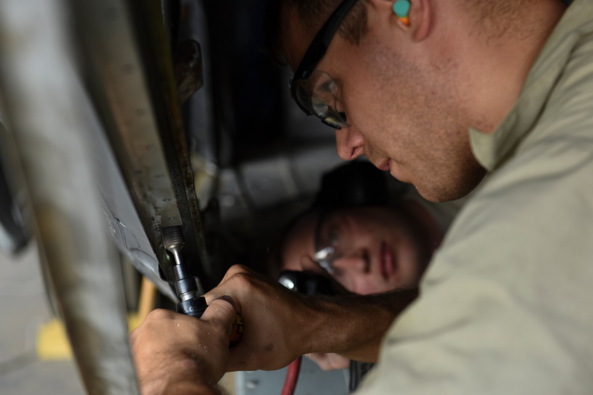 U.S. Air Force Tech. Sgt. Cameron Blanton, 386th Expeditionary Maintenance Squadron combat metals flight aircraft structures craftsman, grinds a piece of metal on an EC-130H Compass Call aircraft June 30, 2018, at an undisclosed location in Southwest Asia. After repairs are finished, the aircraft is scheduled to be retired to the Davis-Monthan Air Force Base, Arizona boneyard later this year. (U.S. Air Force photo by Tech. Sgt. Caleb Pierce)