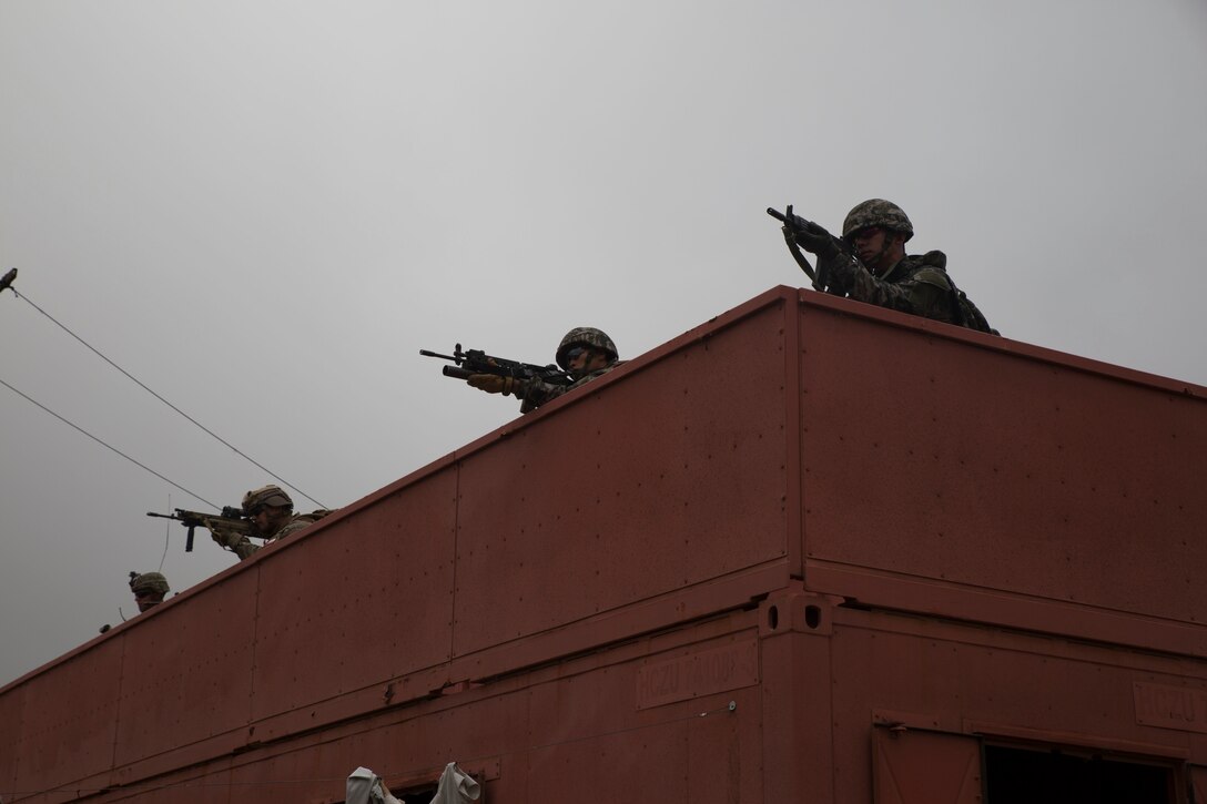 Republic of Korea, Chilean and U.S. Marines provide security from a rooftop during a noncombatant evacuation operation (NEO) training event as part of Rim of the Pacific (RIMPAC) exercise at Pohakuloa Training Area, Hawaii, July 12, 2018. A NEO is conducted to evacuate citizens whose lives are in danger. RIMPAC provides high-value training for task-organized, highly capable Marine Air-Ground Task Force and enhances the critical crisis response capability of U.S. Marines in the Pacific.
