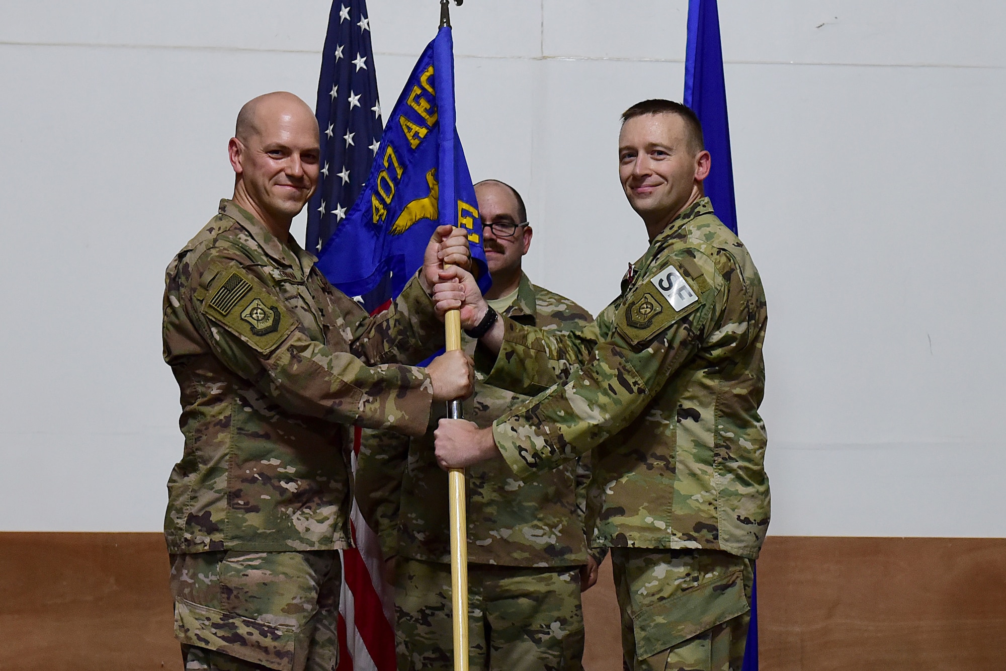 Two Airmen hold on to a squadron flag