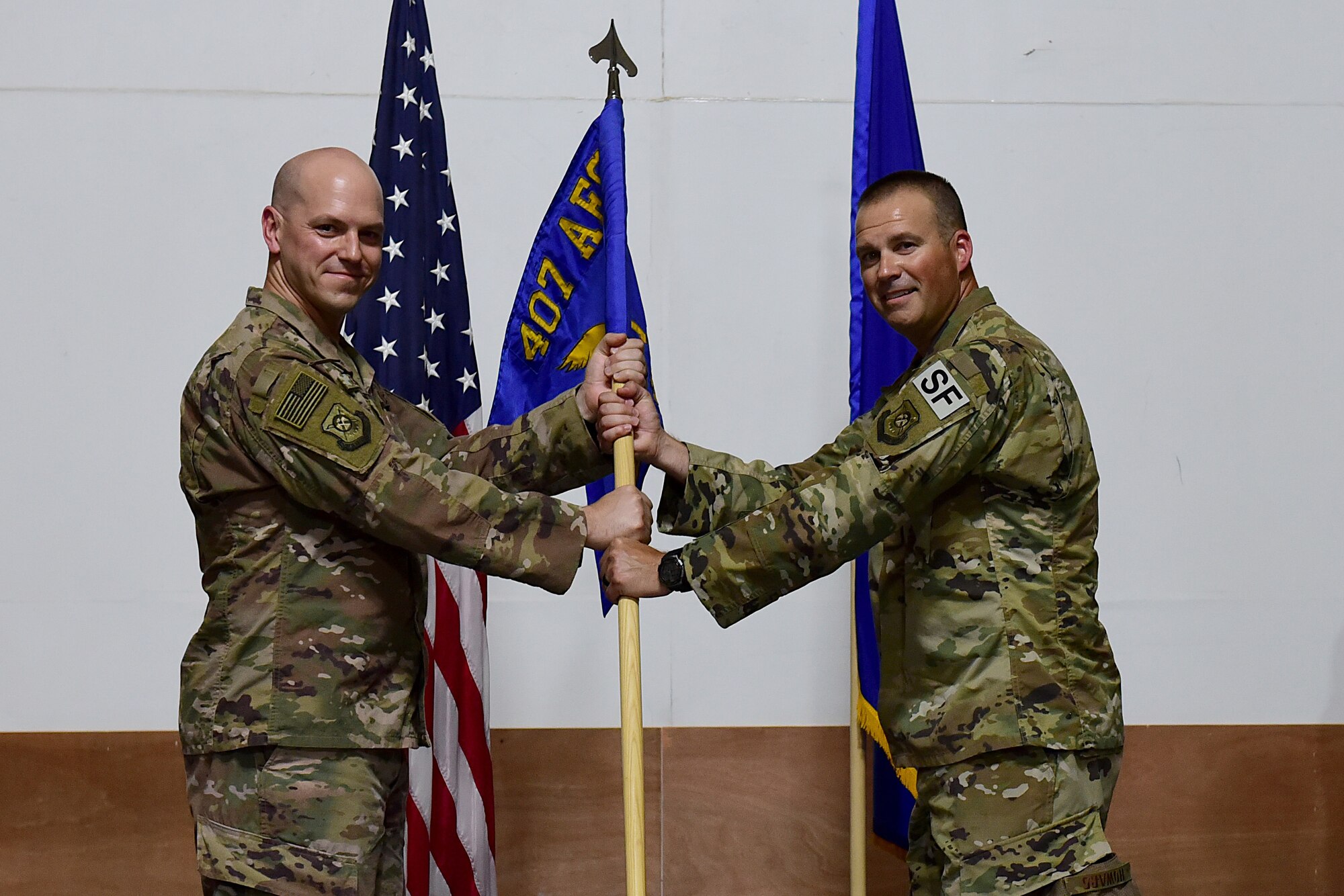 Two Airmen hold on to a squadron flag