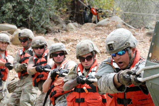 A row of service members pull on a rope.