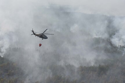 A New York Army National Guard  UH-60  assigned to 3rd Battalion, 142nd Aviation, flies over a 526-acre forest fire in Flat Rock State Forest in Altona, N.Y., on July, 13, 2018 during a fire fighting mission.  Two UH-60s  responded to a forest fire that broke out in Altona, N.Y., on July 12 on July 13 and again on July 15.