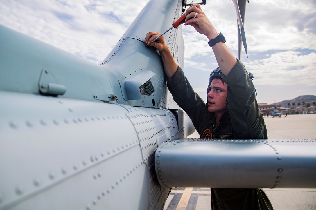 A Marine secures a panel on to a UH-1Y Venom helicopter.