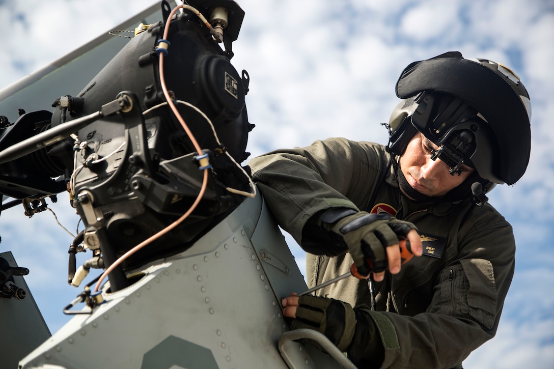 A Marine pilot secures a panel on to an AH-1Z Viper helicopter.