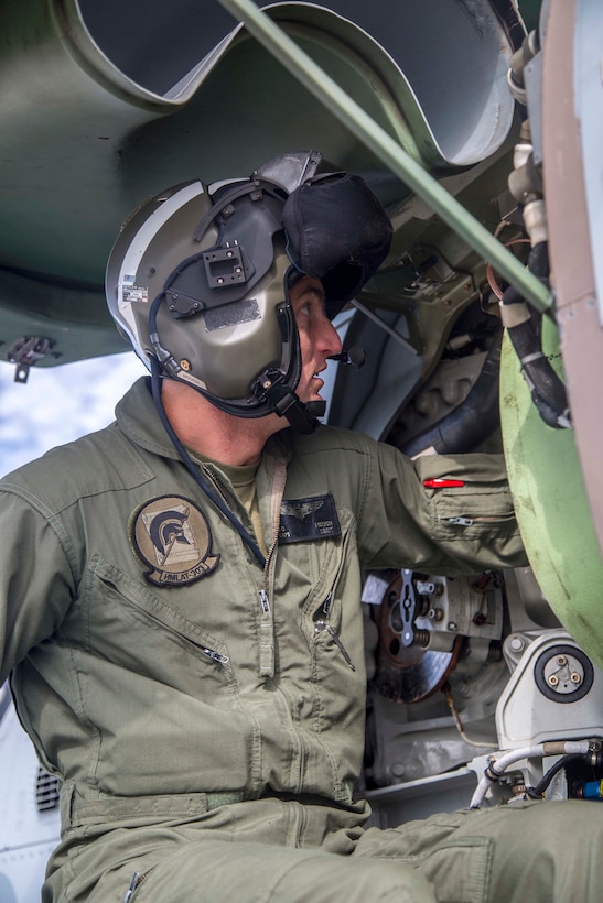 A Marine pilot examines the inner components of an AH-1Z Viper helicopter.