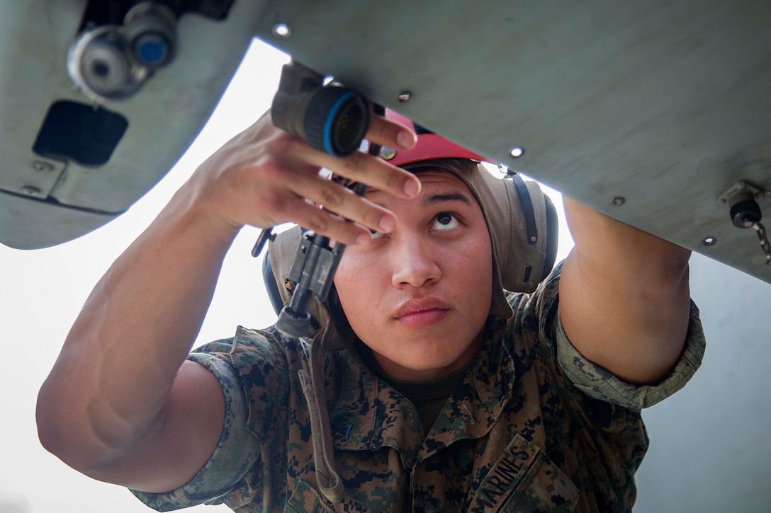 A Marine repairs a launcher mount on an AH-1Z Viper helicopter.