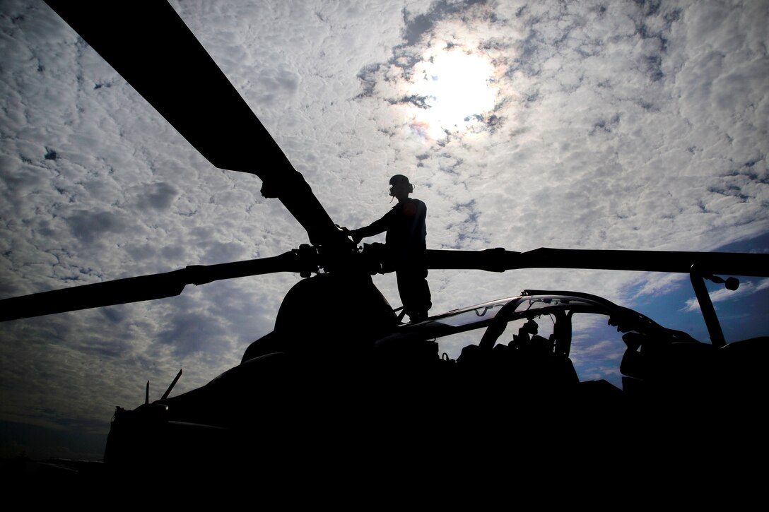 A Marine inspects the main rotor of an AH-1Z Viper helicopter.