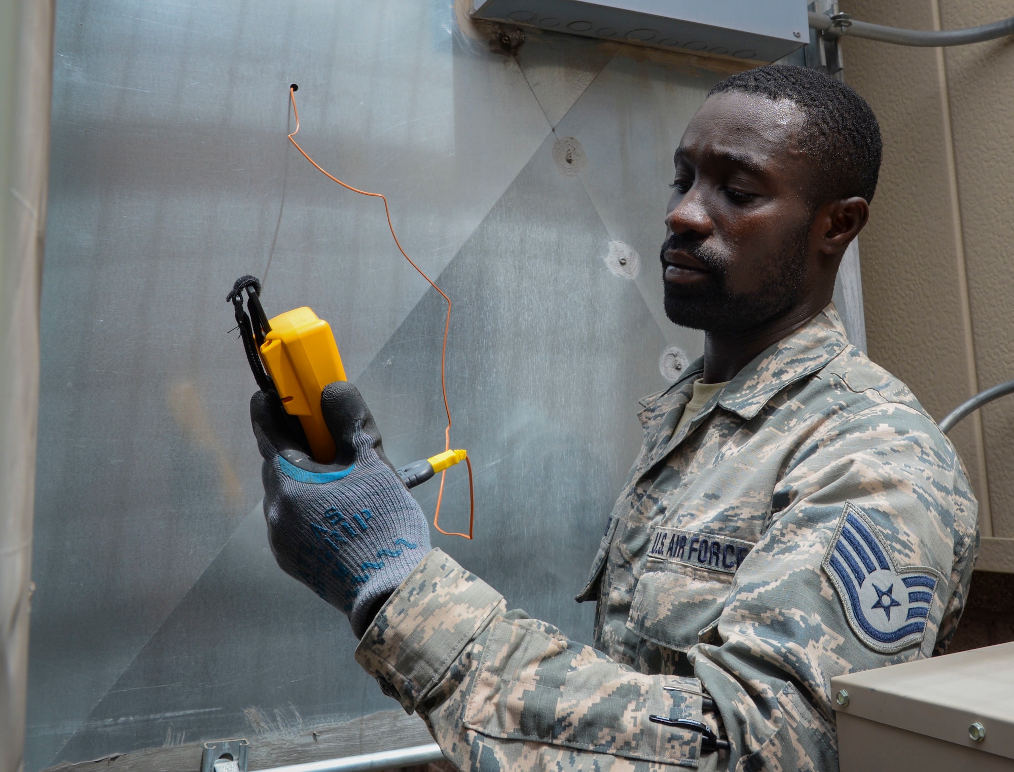 Staff Sgt. Cheick Kamagate, Heating, Ventilation, Air Conditioning/Refrigeration and Control technician assigned to the 512th Civil Engineer Squadron Reserve Unit at Dover Air Force Base, Delaware checks the air supply temperature going into a 57th maintenance facility on Nellis Air Force Base. The 99th CES HVAC shop has prepared for the summer heat by utilizing over 50 Air Reserve Component technicians across 13 other bases. (U.S. Air Force photo by Airman Bailee A. Darbasie)