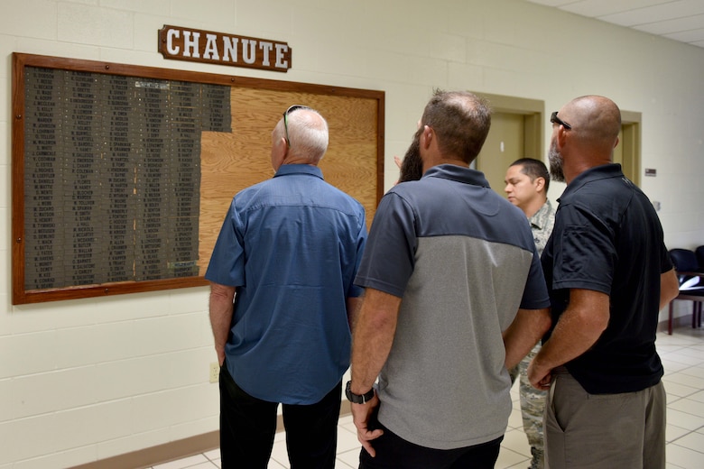 Louis Garland, Nathan Garland, Clayton Garland, decedents of late Chief Warrant Officer Louis F. Garland, and U.S. Air Force Master Sgt. Roy Campos, 312th Training Squadron advance courses chief, view a list of names in the Louis F. Garland Department of Defense Fire Academy on Goodfellow Air Force Base, Texas, July 13, 2018. The names belong to firefighter instructors from Chanute Air Force Base, Illinois, the previous home of the fire academy before Goodfellow. (U.S. Air Force photo by Senior Airman Randall Moose/Released)