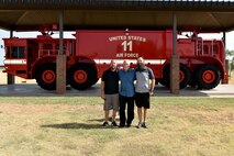 Clayton Garland, Louis Garland and Nathan Garland, decedents of late Chief Warrant Officer Louis F. Garland, pose before a P-15 Mammoth at the Department of Defense Fallen Firefighter Memorial on Goodfellow Air Force Base, Texas, July 13, 2018. The memorial houses firefighting equipment from the past and stands to honor military and DoD firefighters who died in the line of duty. (U.S. Air Force photo by Senior Airman Randall Moose/Released)