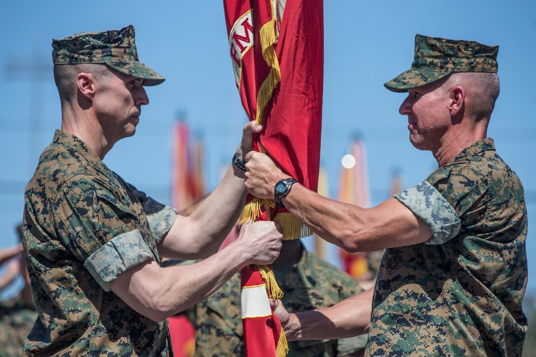 U.S. Marine Corps Maj. Gen. Robert F. Castellvi, left, the incoming commanding general of 1st Marine Division, recieves the division colors from Maj. Gen. Eric M. Smith, the outgoing commanding general, during a change of command ceremony held at Marine Corps Base Camp Pendleton, Calif., July 6, 2018.