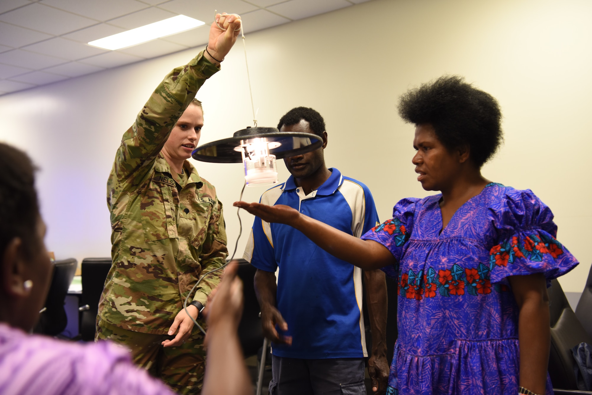 U.S. Army Spc. Marlee Nelson, U.S. Army Public Health Command Pacific preventive medicine specialist, Joint Base Lewis-McChord, Wash., shows a group of vector-borne disease control professionals from Luganville, Vanuatu, a mosquito U.V. light trap during a subject matter exchange as part of Pacific Angel (PAC ANGEL) 18-3 in Luganville, Vanuatu, July, 10, 2018.