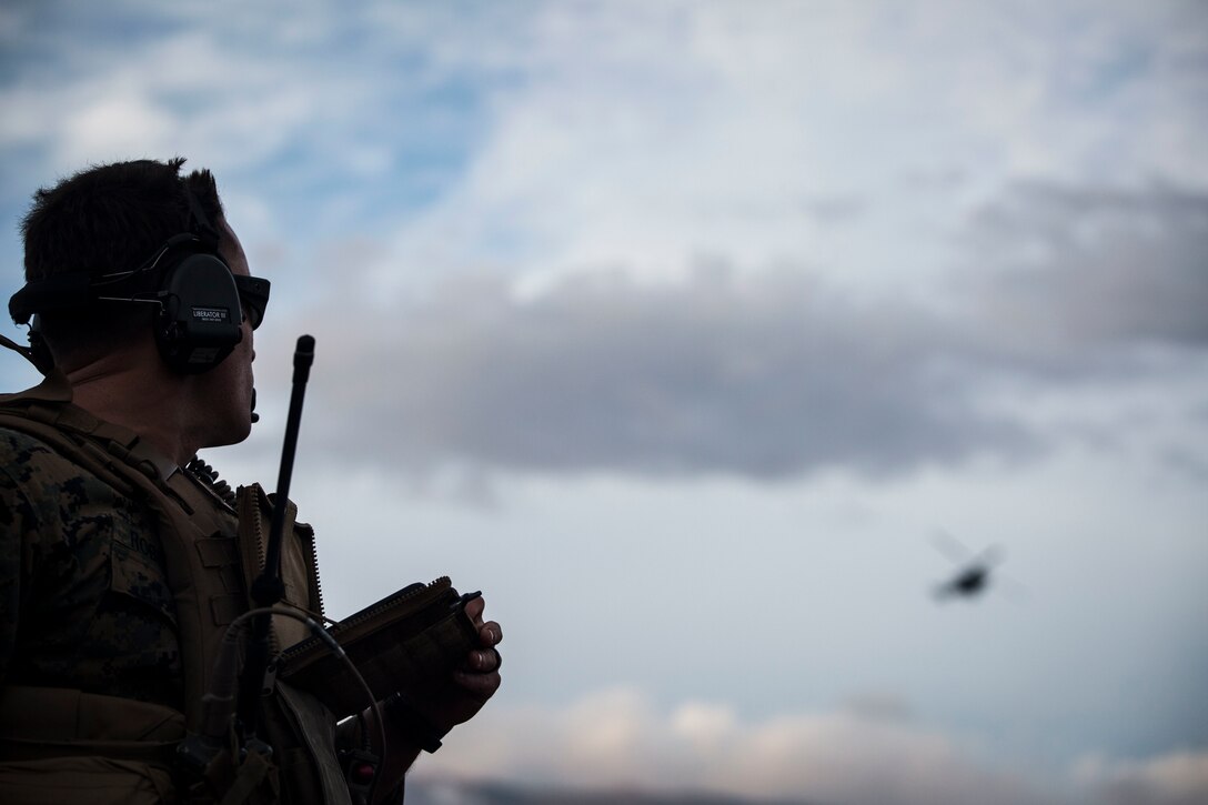 A U.S. Marine watches a UH-1Y Huey fly towards an impact area during close air support as part of Rim of the Pacific (RIMPAC) exercise at Pohakuloa Training Area, Hawaii, July 14, 2018. The training involved pilots working with a joint forward air controller to coordinate the close air support of ground troops.