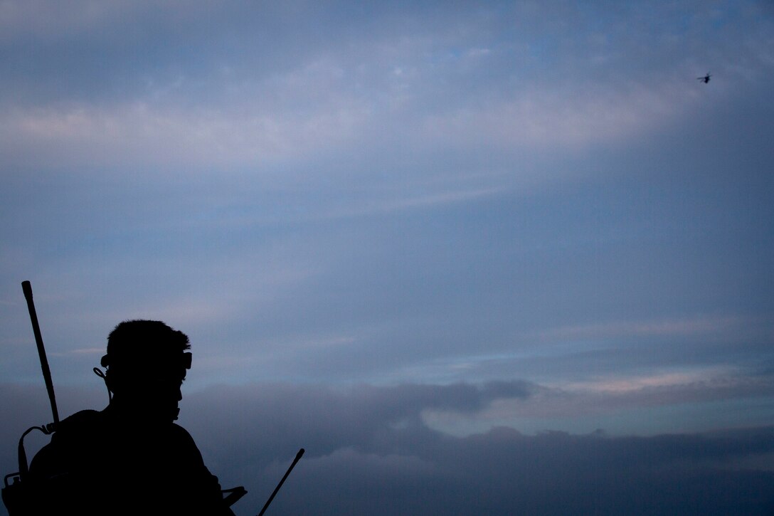 A U.S. Marine observes a UH-1Y Huey fly towards an impact area during close air support as part of Rim of the Pacific (RIMPAC) exercise at Pohakuloa Training Area, Hawaii, July 14, 2018. The training involved pilots working with a joint forward air controller to coordinate the close air support of ground troops.
